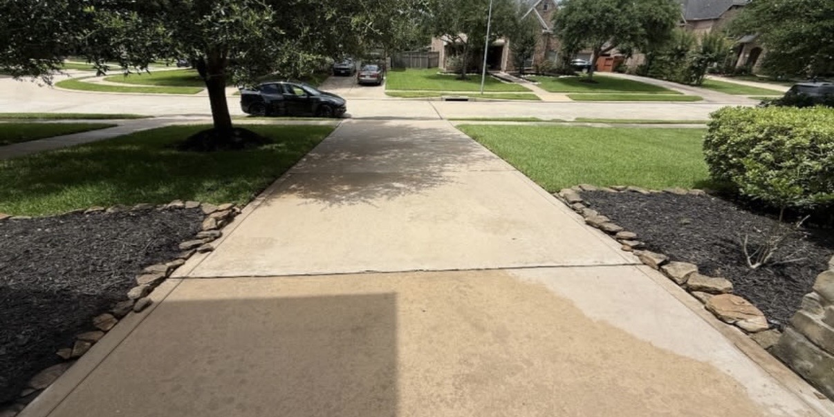 A freshly pressure-washed driveway surrounded by green lawns